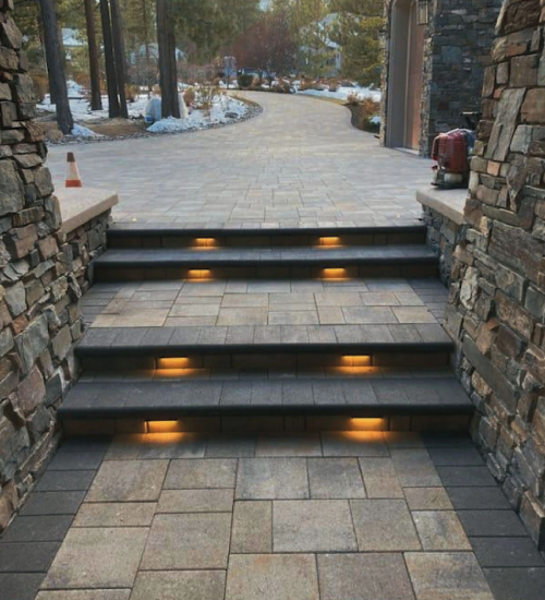 A walkway with steps and lights leading to the side walk.